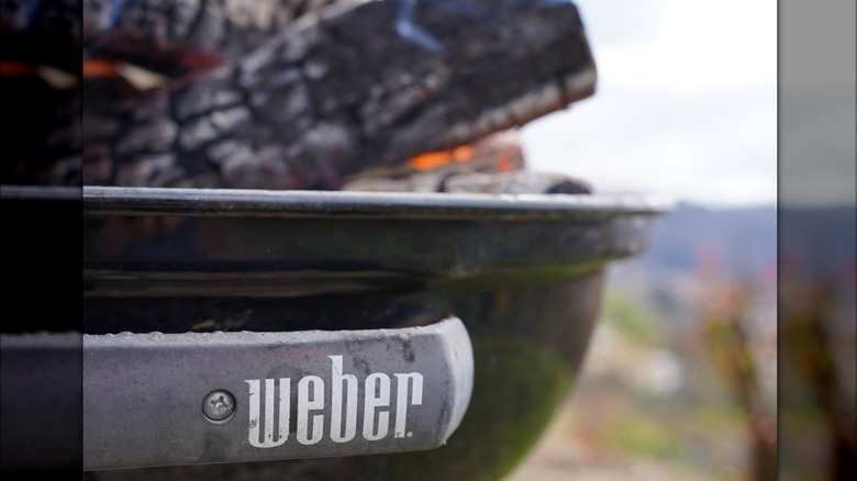 A Weber Kettel Grill with burning logs inside