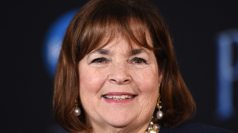 Ina Garten smiling with her hair down while wearing a pearl necklace and matching earrings