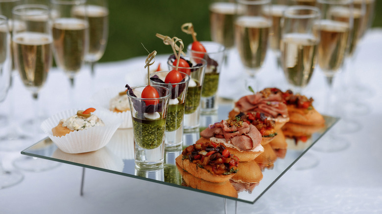 appetizers on a mirrored tray, including one in a shot glass