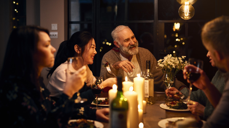 guests sitting at dinner party table lit by candles