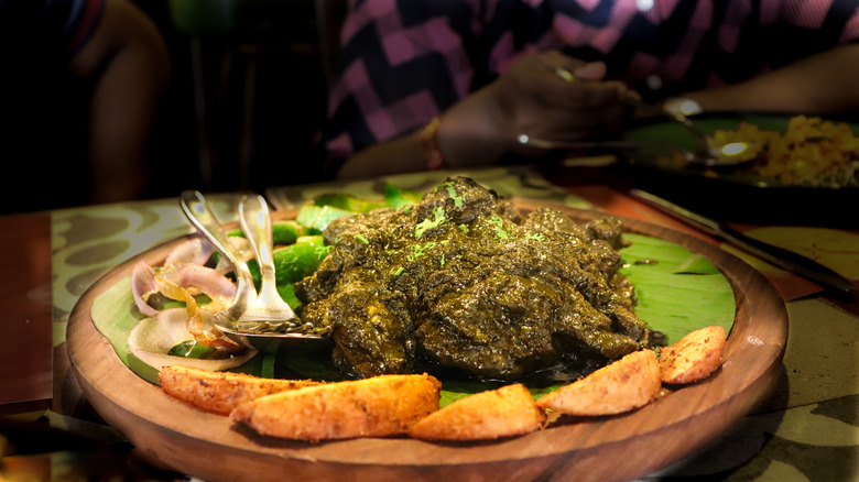 Chicken cafreal served on banana leaf alongside potato wedges and raw onions