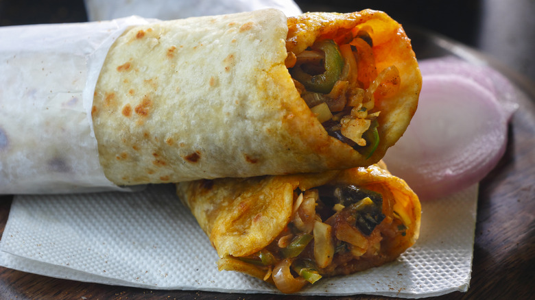 Mixed vegetables inside roll, served alongside raw onion on napkin