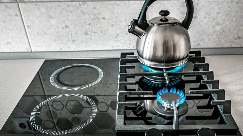 A modern stove has gas and induction options, water boiling on gas burner.