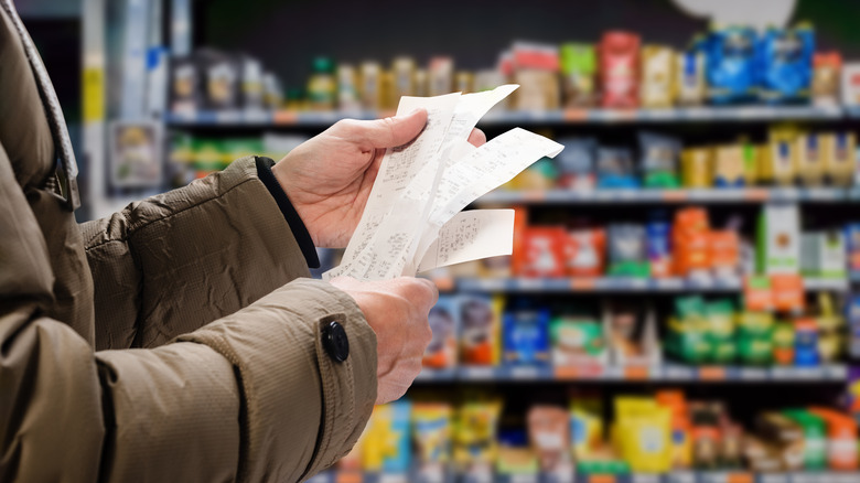 A customer holding receipts in a grocery store 