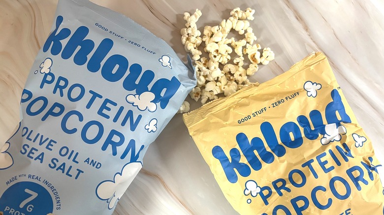 Bags of Khloud popcorn and popcorn pieces on marbled surface