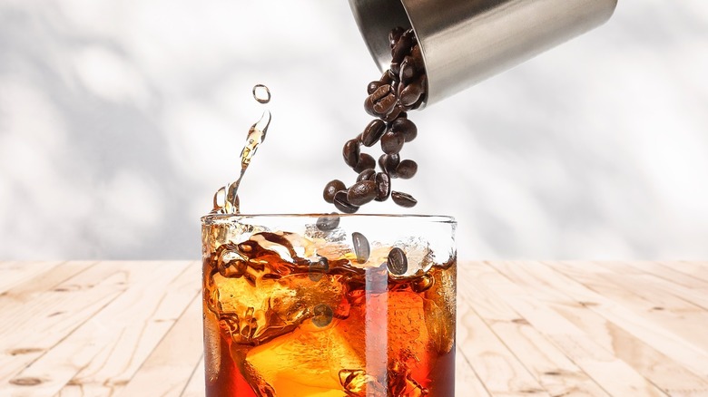 Coffee beans pouring into a glass of bourbon