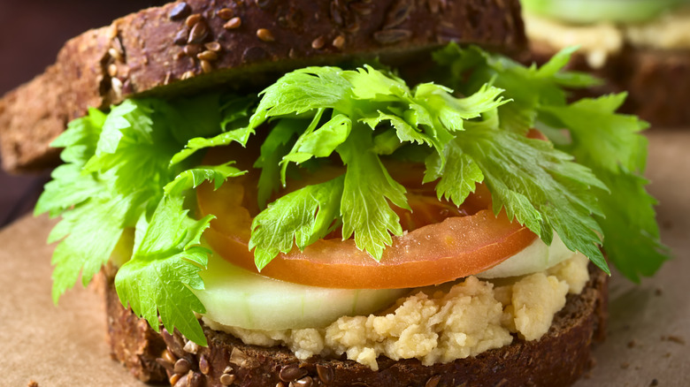 Mashed chickpea sandwich with lettuce, tomato, and onion on seeded bread