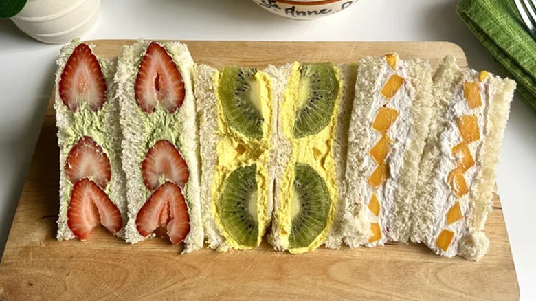 Three colorful Japanese fruit sandwiches on a cutting board