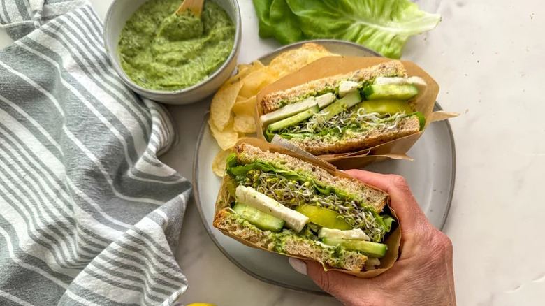 Hand holding vegetarian sandwich with green goddess dressing