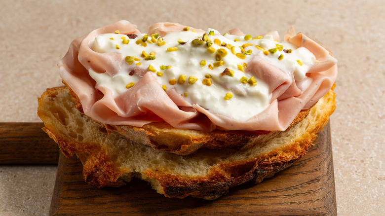 Open sandwich with fresh cheese, mortadella, and crushed pistachios