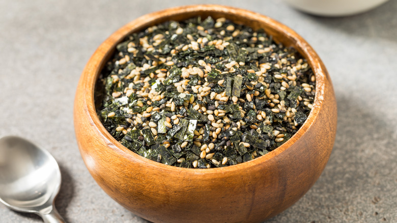 Wooden dipping bowl filled with furikake next to a metal spoon