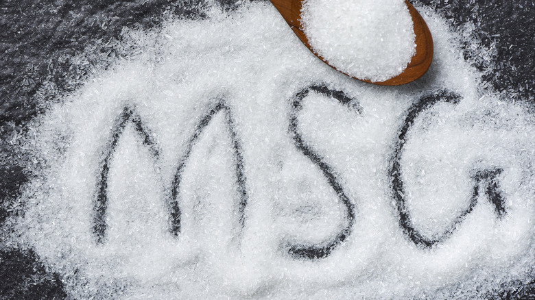 Pile of white powder with MSG drawn into it next to a wooden spoon