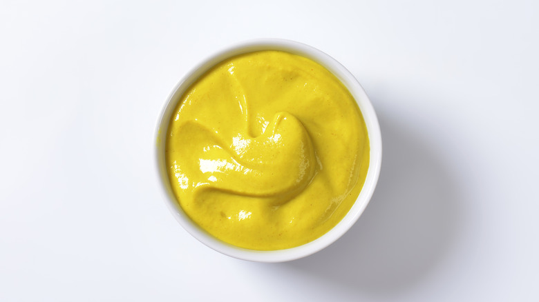 Top view of a bowl of mustard on a white background