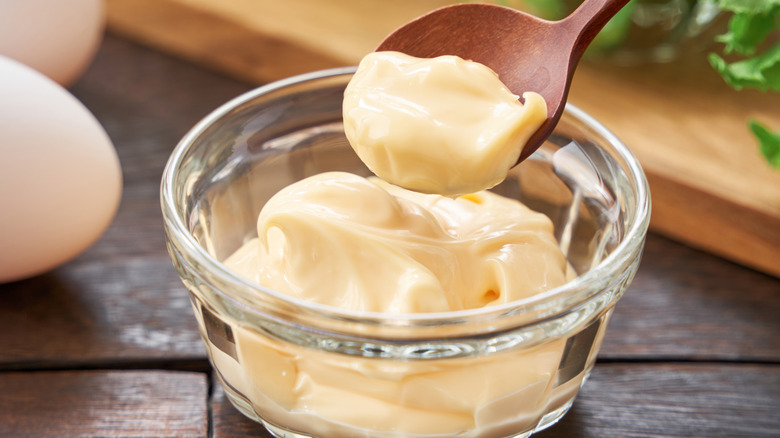 Spooning mayonnaise from small glass bowl