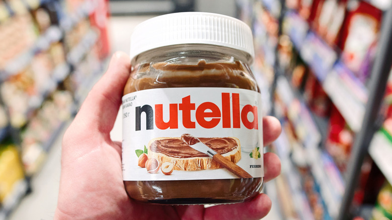 Hand holding jar of Nutella in supermarket