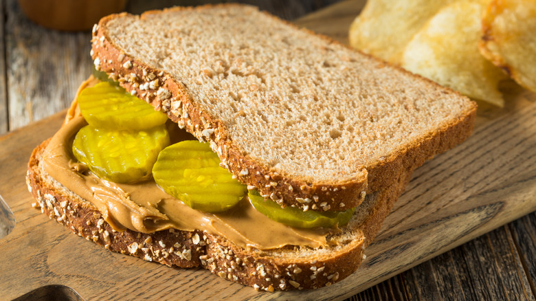 Peanut butter and pickle sandwich on wooden cutting board