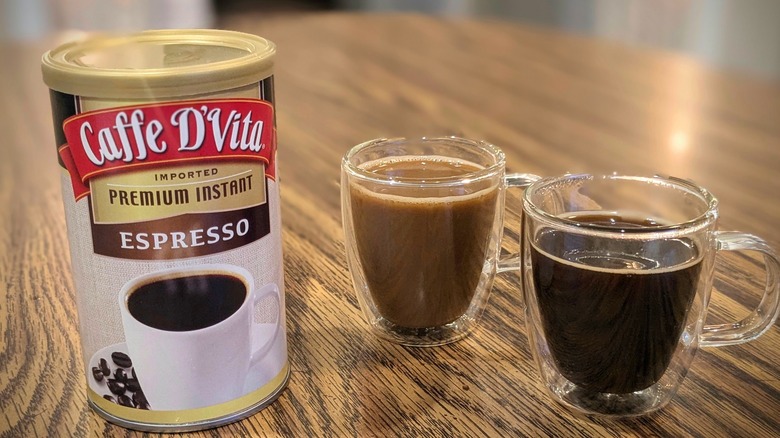 Two espresso cups and Caffe D'Vita instant espresso container on wood table
