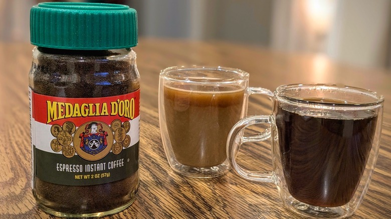 Medaglia D'Oro instant coffee jar and two espresso cups on wood table