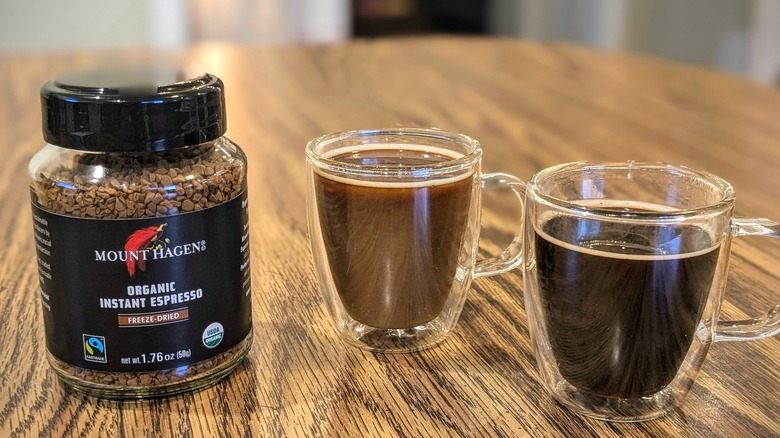 Two espresso cups and Mount Hagen instant coffee jar on wood table