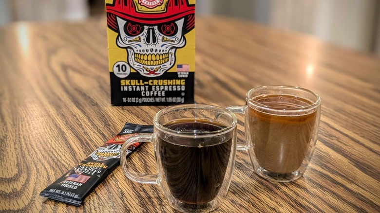 Two espresso cups on wood table with Fire Department coffee box in background