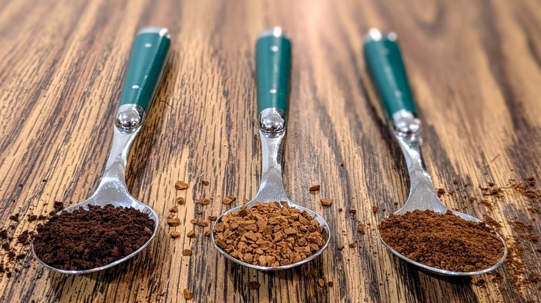 Different-colored coffee granules in spoons resting on wood table