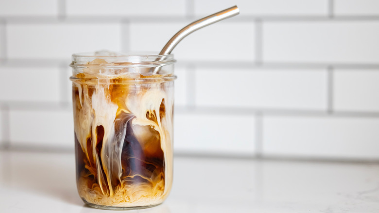 A jar of iced coffee with a straw
