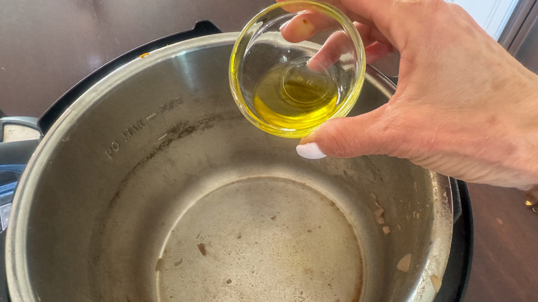 hand adding oil to instant pot