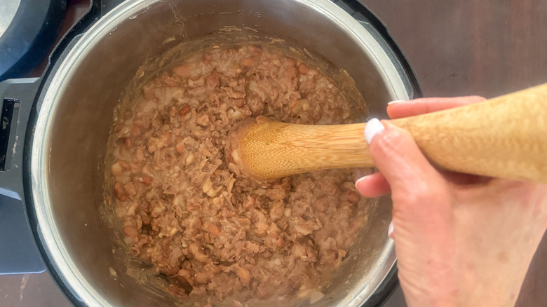 hand mashing beans in pot