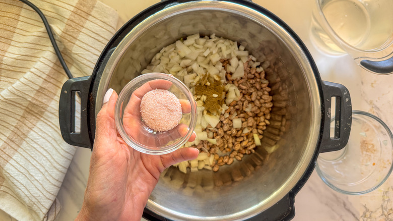 hand adding salt to pot