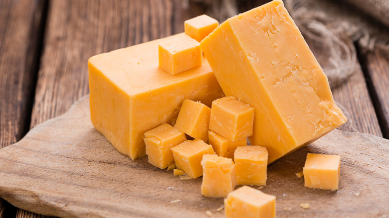 Two large blocks and several smaller cubes of cheddar cheese