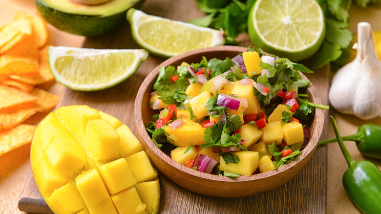 A bowl of mango salsa on a wooden board