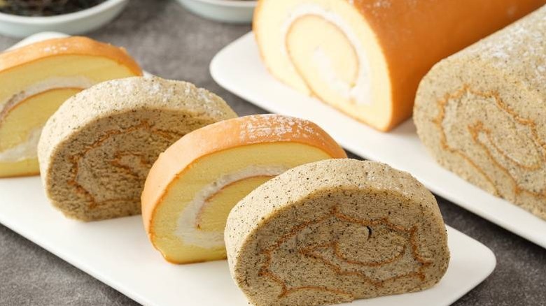 Slices of coconut and teal roll cakes placed on a white platter