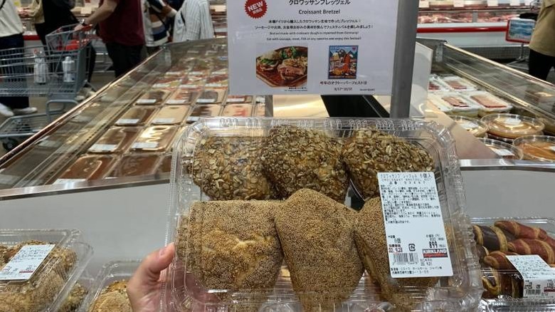 A hand holding a box of croissant bretzels at a Costco bakery