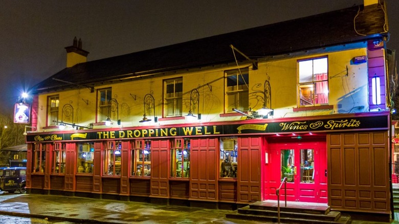 Exterior of The Dropping Well at night with lights on