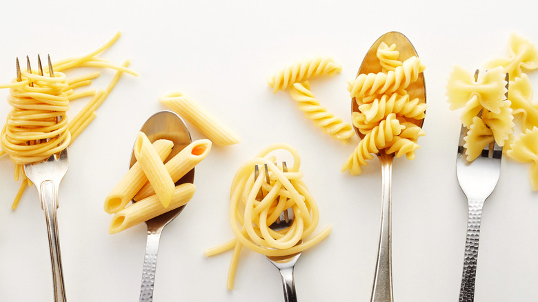 Top-down view of five types of pasta noodles on spoons