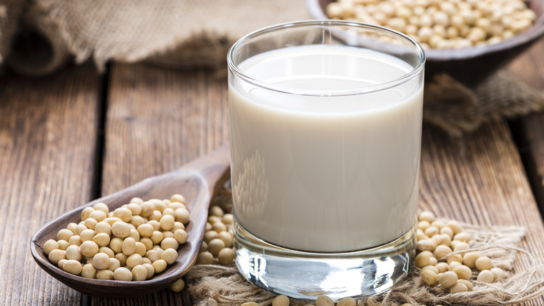 glass of soy milk next to soybeans