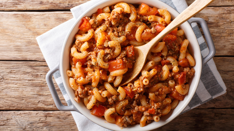 A pot of American goulash, or American chop suey, resting on a wooden table