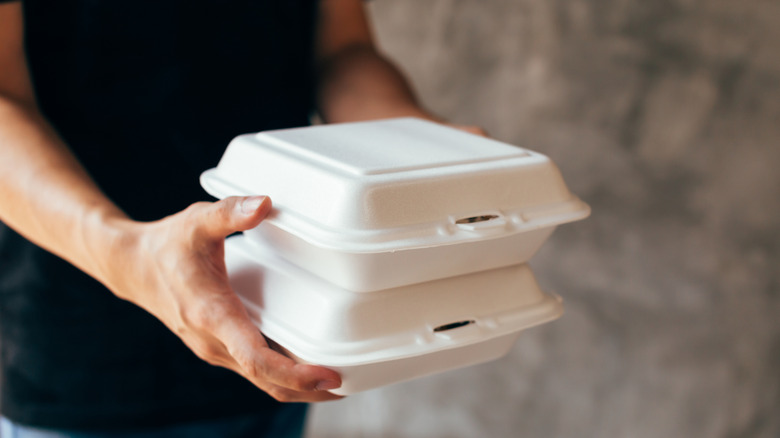 Someone carrying two Styrofoam takeout boxes