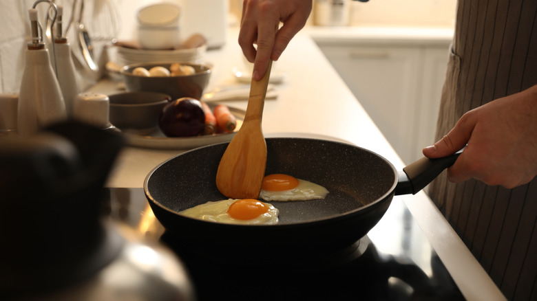A man frying eggs in a ceramic nonstick pan