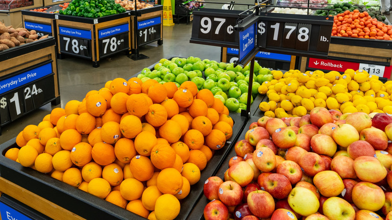 Display of produce including crates of oranges, apples, and lemons inside Walmart store
