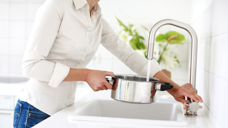 person filling pot from tap