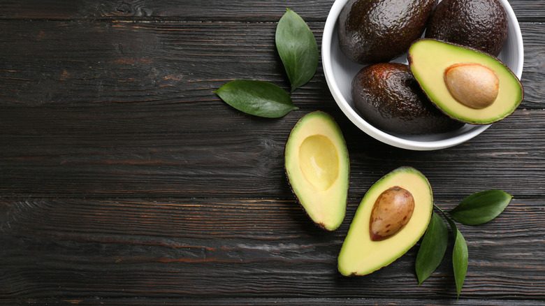 Avocados whole and halved in a bowl 