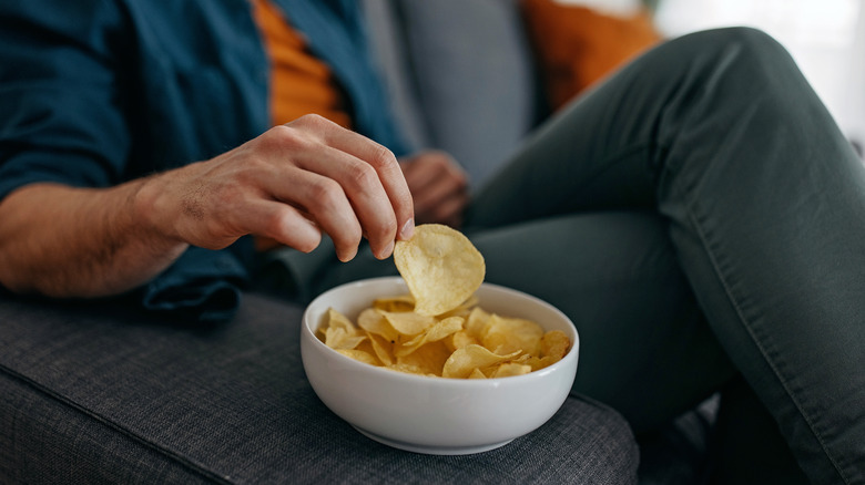 Person eating potato chips out of a bowl