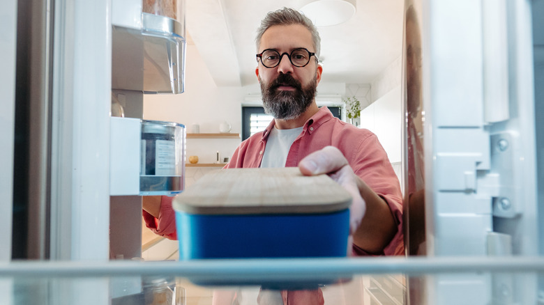 Person taking a container of leftovers out of the fridge