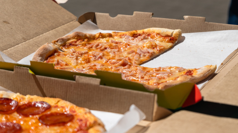 leftover pizza in cardboard takeout box