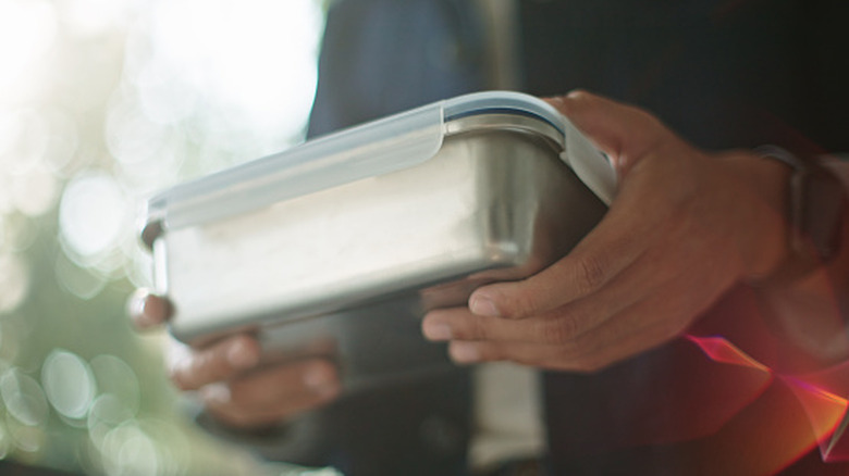Close-up photo of person holding a steel food container with both hands