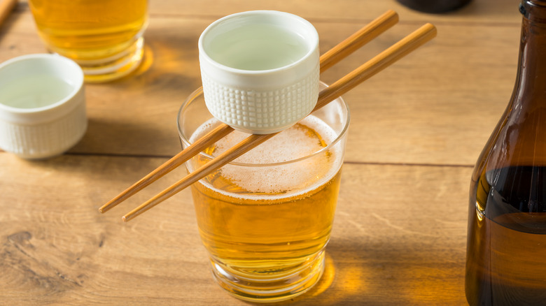 small white cup sitting on top of chopsticks over larger glass