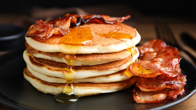 stack of pancakes with bacon and syrup