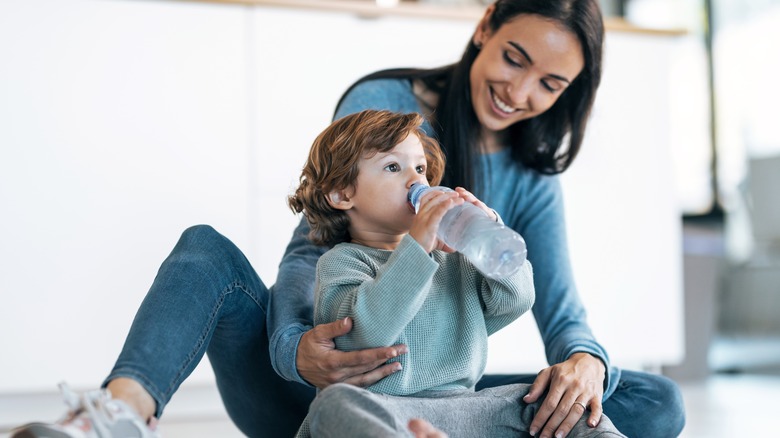 Woman with her child drinking from a plastic bottle filled with water