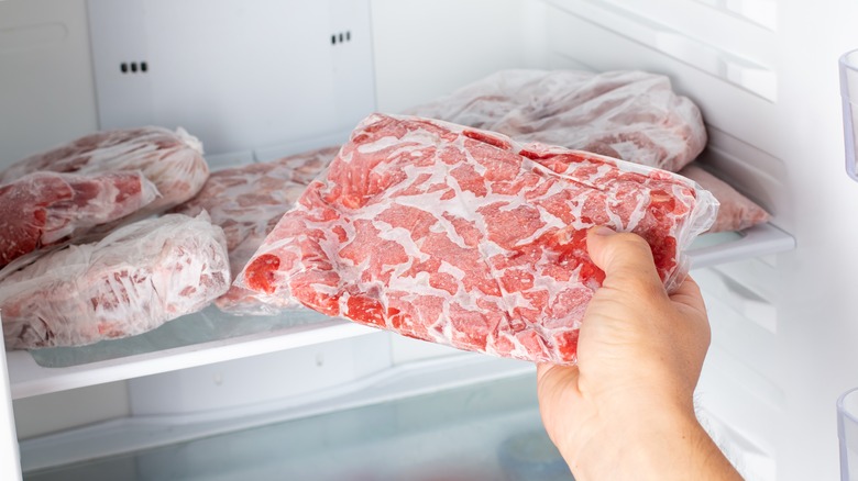 Hand taking frozen meat from freezer